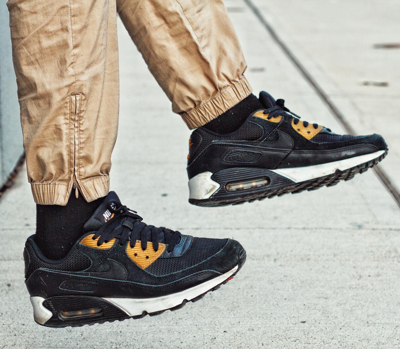 Casual street style with black and gold sneakers in motion.