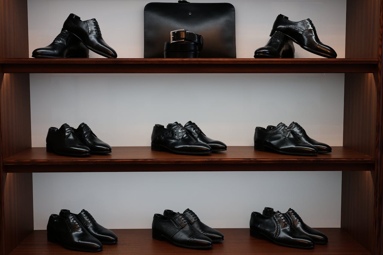 services-01 A stylish display of black leather shoes and accessories on wooden shelves in a store.