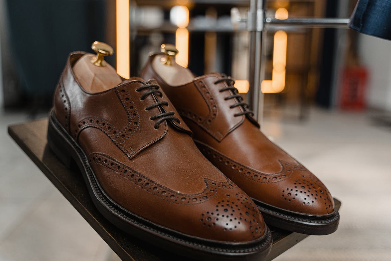 Classic brown leather brogue shoes with detailed perforations on a stylish display.