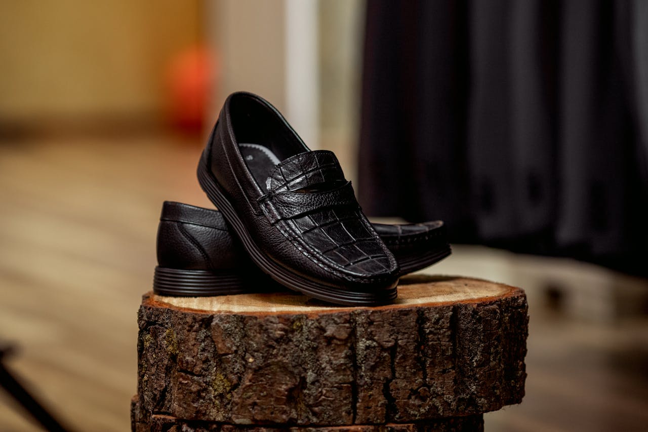 heros-img Stylish black loafers displayed on wood, highlighting detailed craftsmanship.